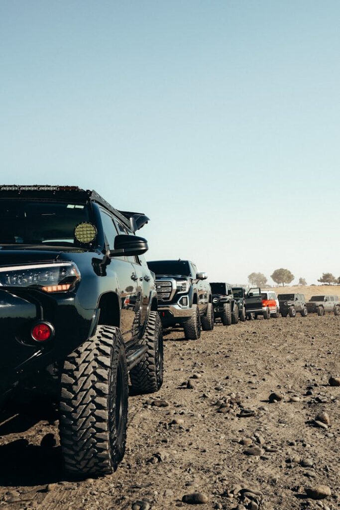 Offroad vehicles lined up on rugged, rocky terrain under a clear blue sky.